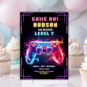 May include: A neon pink and blue video game party invitation with a glowing game controller and the text "GAME ON! HUDSON HAS REACHED LEVEL 7". The invitation includes the date, time, and location of the party.