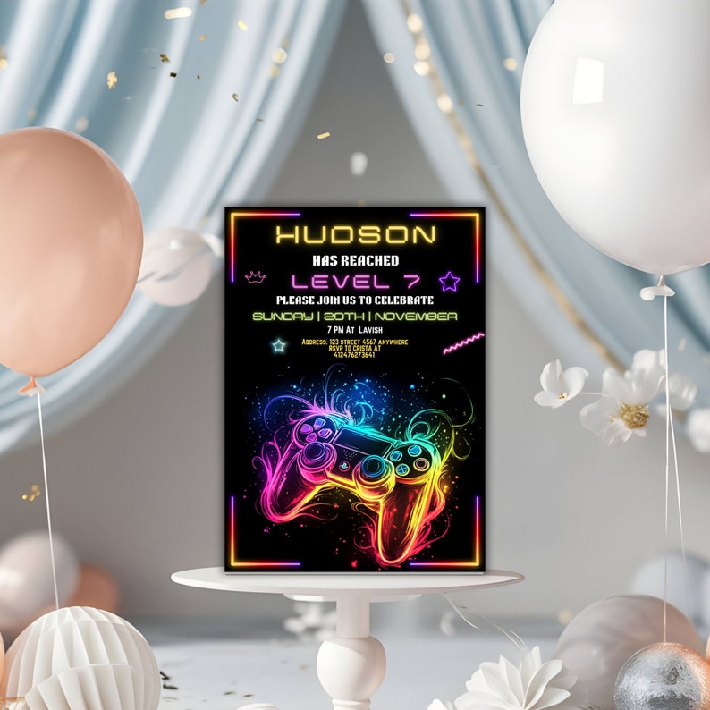 May include: A neon-colored video game controller graphic on a black background with the text "HUDSON HAS REACHED LEVEL 7" in a neon font. The text below reads "PLEASE JOIN US TO CELEBRATE SUNDAY | 20TH NOVEMBER 7 PM AT LAVISH ADDRESS 123 STREET 4567 ANYWHERE RSVP TO CRISTA AT 412478273641".