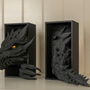 May include: Two black wooden shadow boxes with a dragon sculpture inside. The dragon's head is visible in one box, and the tail is visible in the other box.