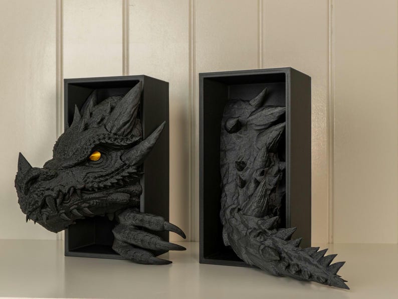 May include: Two black wooden shadow boxes with a dragon sculpture inside. The dragon's head is visible in one box, and the tail is visible in the other box.