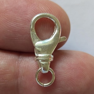 Op de afbeelding: Zilverkleurige karabijn sluiting met een ronde springring. Deze sluiting wordt vaak gebruikt voor het maken van sieraden.