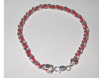 May include: A silver chain bracelet with a red braided cord. The bracelet has a lobster clasp closure.