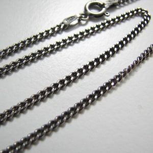 Puede incluir: Un collar de cadena de plata con cierre de langosta. La cadena es de estilo curb con un dise&ntilde;o trenzado.