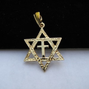 Peut inclure: Un pendentif en or représentant une étoile de David avec une croix à l'intérieur. Le pendentif a un design détaillé et texturé.