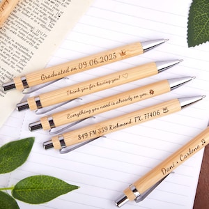 May include: Several bamboo pens with silver details. Each pen is engraved with a unique message, such as "Graduated on 09.06.2025", "Thank you for having you!", and "Everything you need is already on you."