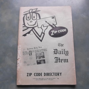 May include: A vintage book titled "The Daily Item ZIP CODE DIRECTORY" with a cartoon illustration of a person holding a letter with a zip code on it. The book cover is beige with black text and illustrations.