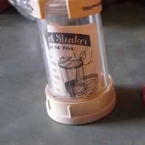 May include: White plastic spice shaker with a clear glass container. The shaker has a black and white label that says "Spice Shaker" and "Easy to Fill".