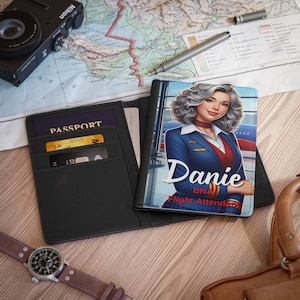 Könnte beinhalten: Schwarzer Reisepass-Etui mit einer goldenen Karte und dem Wort "PASSPORT" auf der Vorderseite. Das Etui ist geöffnet und zeigt ein zweites Reisepass-Etui mit einem bunten Bild einer Flugbegleiterin mit dem Namen "Danie BNA Flight Attendant" auf der Vorderseite.