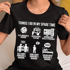 May include: Black t-shirt with white text and graphics. The shirt reads "THINGS I DO IN MY SPARE TIME" above illustrations of dice, a computer screen, and people. The theme is Dungeons & Dragons.