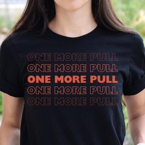 Könnte beinhalten: Schwarzes T-Shirt mit dem orangefarbenen Text "ONE MORE PULL", fünfmal wiederholt. Das T-Shirt hat kurze Ärmel und einen Rundhalsausschnitt. Der Text ist in einer fetten, serifenlosen Schriftart.