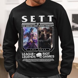 May include: Black sweatshirt featuring the name "SETT" in white block letters. Below the name are the phrases "PIT GRIT - KNUCKLE DOWN - HAYMAKER - FACEBREAKER - THE SHOW STOPPER". The sweatshirt also features images from the game League of Legends.