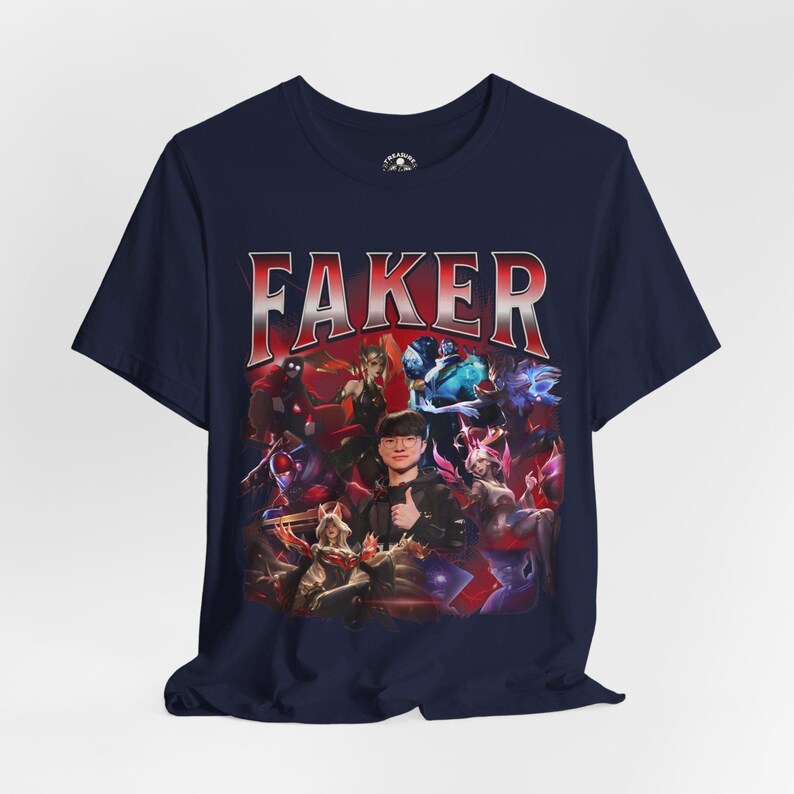 Op de afbeelding: Een marineblauw t-shirt met een grafische print van een League of Legends-speler, Faker, omringd door personages uit het spel. De tekst "FAKER" is in rode en witte letters boven de print gedrukt.