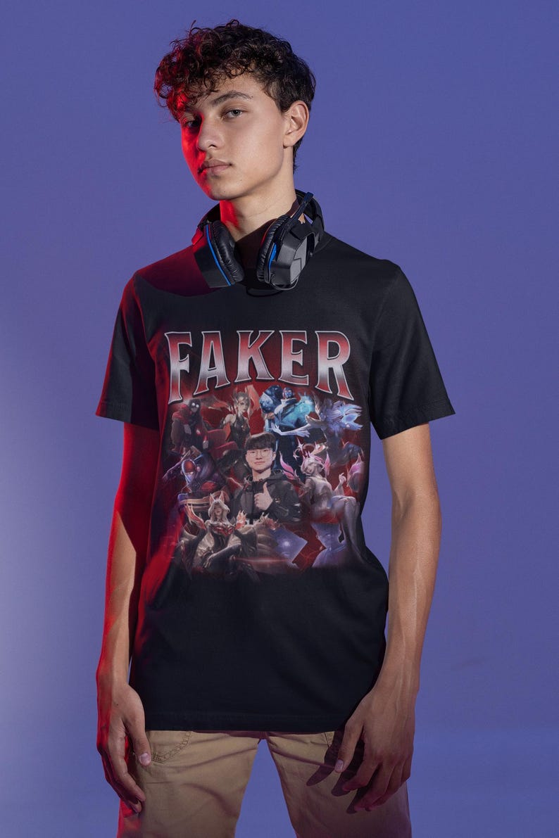 Op de afbeelding: Zwart T-shirt met een grafische print van een videogamepersonage, "Faker", en andere personages. Het shirt heeft een rood-wit verloopontwerp.