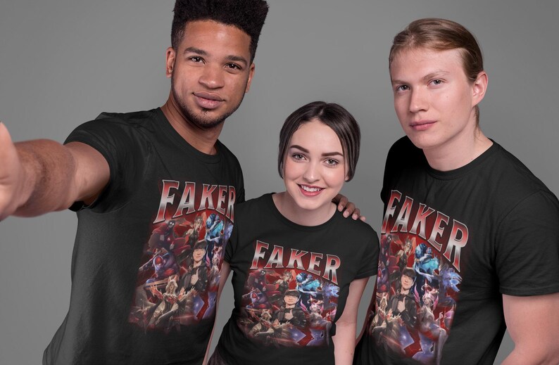 Op de afbeelding: Drie mensen dragen zwarte T-shirts met een grafische print van een videogamepersonage en het woord "Faker" in rode en witte letters.