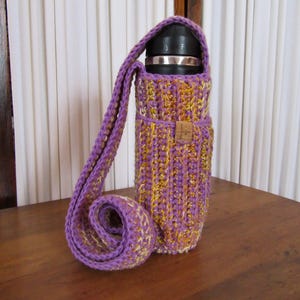 May include: Purple and yellow crocheted insulated bottle carrier with a shoulder strap.