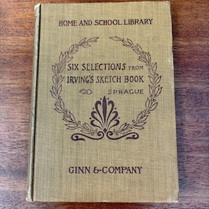 May include: A vintage book titled "Six Selections from Irving's Sketch Book" with the text "Home and School Library" and "Ginn & Company." The cover is a muted olive green with dark brown text and decorative elements.