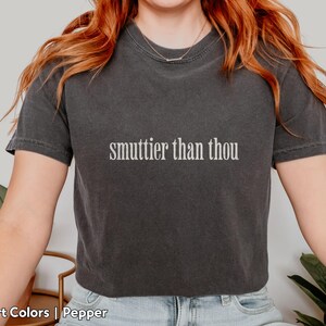 Puede incluir: Camiseta gris oscuro con la frase "smuttier than thou" impresa en blanco. La camiseta es de la marca Comfort Colors en el color Pepper. La persona lleva un collar plateado.