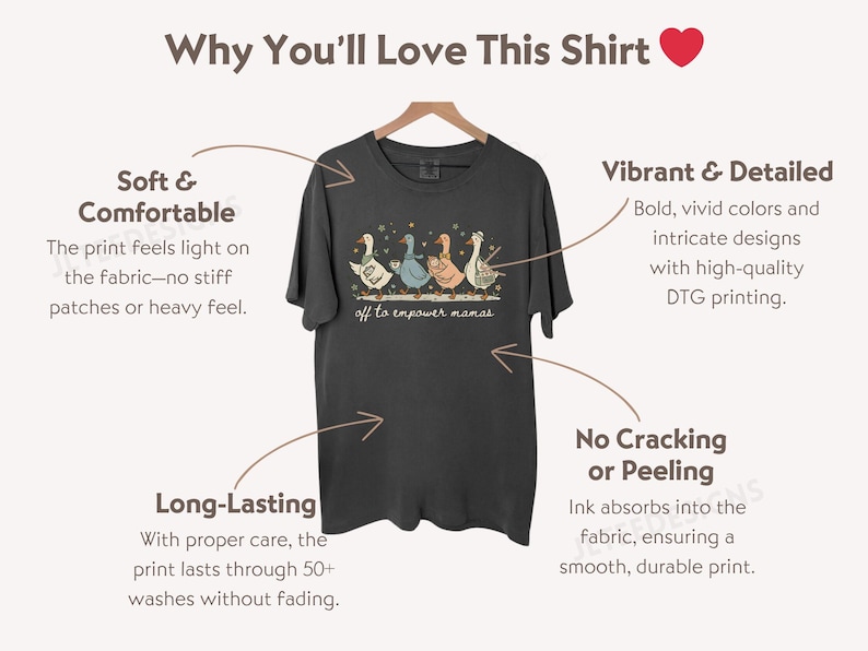May include: Dark gray t-shirt with a whimsical design of three geese holding musical instruments, with the text "off to empower mamas." The shirt is displayed on a wooden hanger.