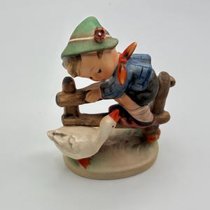 May include: A white ceramic mug with a black handle and the text "But First, Coffee" in a black, handwritten-style font. The mug is on a white surface.