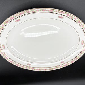 May include: Oval white serving platter with a pink floral border and gold trim. The platter has a smooth, glossy surface and is suitable for serving food. The floral design adds a touch of elegance to the dish.