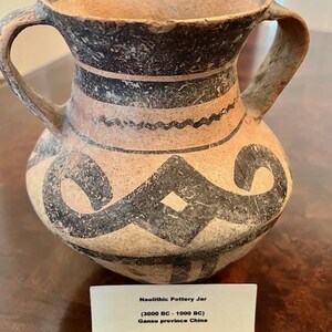 May include: Neolithic Pottery Jar (3000 BC - 1000 BC) Gansu province China. A brown clay jar with two handles and black geometric designs.