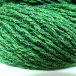 May include: A close-up of a skein of deep green yarn. The yarn is soft and fluffy, and it has a slightly textured surface.