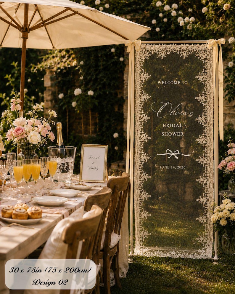 K&ouml;nnte beinhalten: Ein hohes, rechteckiges Willkommensschild aus cremefarbener Spitze f&uuml;r eine Brautparty mit der Aufschrift 'WELCOME TO Olivia's BRIDAL SHOWER' und 'JUNE 14, 2026', aufgeh&auml;ngt an einem Metallrahmen mit B&auml;ndern, Ma&szlig;e 75 x 200 cm.