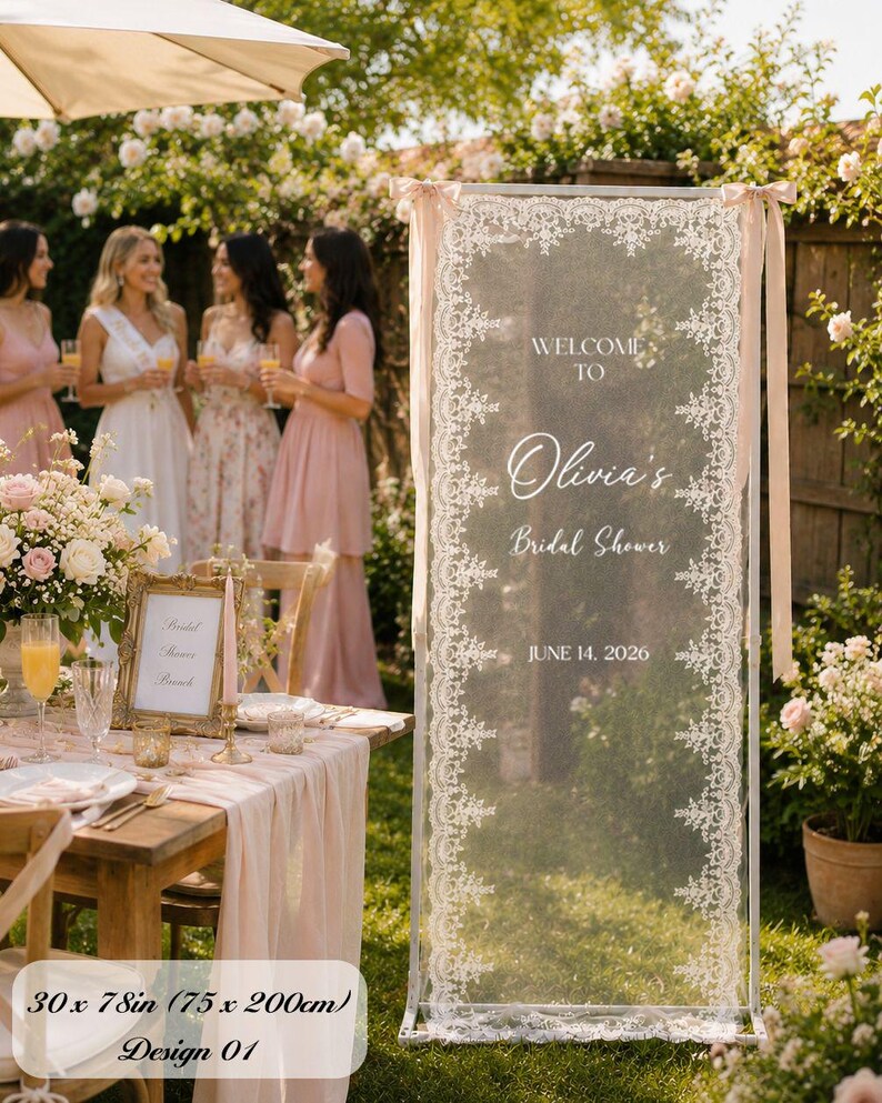 K&ouml;nnte beinhalten: Ein rechteckiges vertikales Schild mit den Ma&szlig;en 75 x 200 cm, bestehend aus einem transparenten wei&szlig;en Stoffpaneel mit aufwendigen Spitzenr&auml;ndern. Das Schild zeigt den Text WELCOME TO Olivia's Bridal Shower JUNE 14, 2026 in wei&szlig;er Schrift.