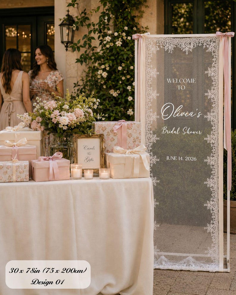 K&ouml;nnte beinhalten: Ein hohes, rechteckiges Hochzeitsschild mit den Ma&szlig;en 75 x 200 cm, das einen wei&szlig;en Spitzenrand auf einer transparenten Platte aufweist. Der Text lautet: WELCOME TO Olivia's Bridal Shower JUNE 14, 2026. Es ist wei&szlig; gerahmt und mit rosa B&auml;ndern verziert.