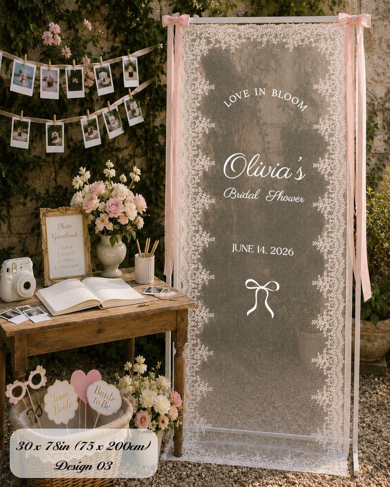 K&ouml;nnte beinhalten: Ein hoher rechteckiger wei&szlig;er Rahmen mit einer transparenten wei&szlig;en Spitzenbahn, bedruckt mit dem Text Love in Bloom, Olivia's Bridal Shower und 14. Juni 2026, akzentuiert durch rosa B&auml;nder an den oberen Ecken, mit einer Gr&ouml;&szlig;e von 75 mal 200 cm.