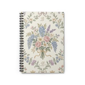Peut inclure: Cahier à spirales avec un motif floral. La couverture présente un bouquet de roses roses, de glycines bleues et d'autres fleurs. Le fond est crème avec des accents floraux, des nœuds et la lettre "B".