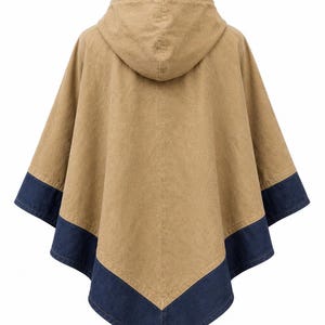 May include: A tan hooded poncho with a dark blue denim trim along the bottom edge. The garment is displayed on a mannequin, highlighting its design and shape. The back view shows the hood and the overall silhouette.