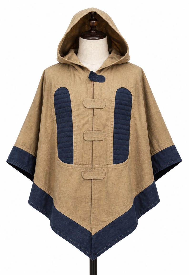 May include: A tan hooded poncho with navy blue detailing. The poncho has a hood, three toggle fastenings, and navy blue quilted panels on the front. The edges are trimmed with navy blue fabric. This outerwear is suitable for various weather conditions.