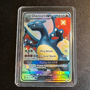 Può includere: Una carta da gioco di scambio Pokemon olografica che presenta Charizard GX, un Pokemon di tipo fuoco con un corpo rosso e arancione e ali blu. La carta ha uno sfondo dorato con stelle e il testo "Charizard GX" in grandi caratteri grassetto. La carta presenta anche il testo "Wing Attack", "Crimson Storm" e "Raging Out GX" con i loro corrispondenti valori di danno dell'attacco.