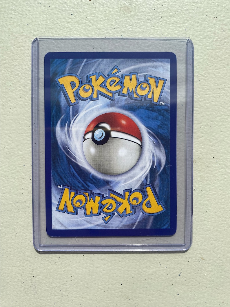 May include: A blue, white, and red Pokemon card back with the word "Pokemon" in white letters and a Pokeball in the center.