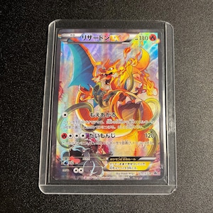 Puede incluir: Una tarjeta coleccionable Pokémon Charizard EX holográfica, en una funda protectora. La tarjeta presenta una ilustración detallada de Charizard en naranja, amarillo y azul, con texto japonés.