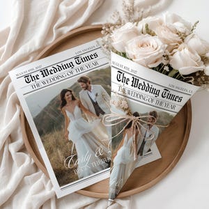 Op de afbeelding: Een trouw-thema krant met de titel "The Wedding Times" met een foto van een bruidspaar. Een boeket crèmerozen wordt gepresenteerd in een kegelvormige krant. De datum "August 8th, 2027" is afgedrukt.