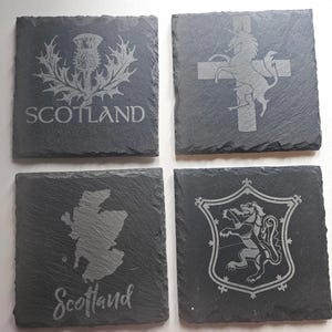 May include: Four square slate coasters with etched designs. One features a thistle and the word "SCOTLAND", another a unicorn and cross, a third a map of Scotland with "Scotland" below, and the last a coat of arms.