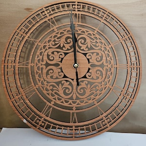 May include: A wooden wall clock with Roman numeral markings and an intricate, laser-cut design. The clock face is brown with black hands.