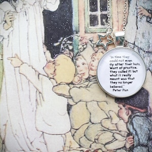 May include: A silver necklace with a round charm featuring a quote from Peter Pan: "In time they could not even fly after their hats. Want of practice, they called it; but what it really meant was that they no longer believed." The charm is attached to a silver chain with a star charm.