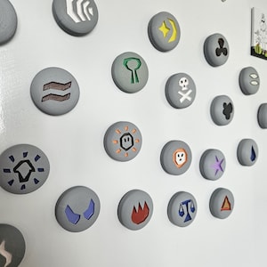 May include: A white refrigerator door with a variety of round, gray magnets with different colored symbols on them. The magnets are arranged in rows and columns. The word "beko" is printed in black on the refrigerator door.