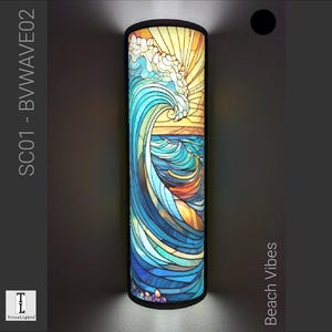 Può includere: Un paralume cilindrico in vetro colorato con un motivo a onda blu e giallo. Il paralume è etichettato "SC01 - B WAVE 02" e "Beach Vibes".