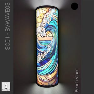 Può includere: Un paralume cilindrico in vetro colorato con un motivo a onda blu e giallo. Il paralume è etichettato "SC01 - B WAVE03" e "Beach Vibes".