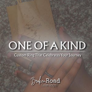 「壊れた道」の旅を象徴するアスファルトインレイ付きのカスタム結婚指輪