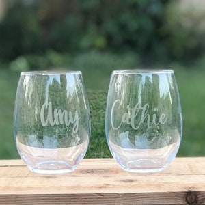 May include: Two clear glass wine glasses with the names "Amy" and "Cathie" etched on them.