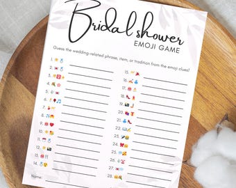 May include: A white paper game sheet for a bridal shower, featuring the words "Bridal Shower Emoji Game" in elegant script. The sheet includes numbered lines with emoji clues for guests to guess wedding-related phrases.