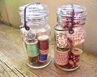 2-5" GLASS JARS- with gLass Lids and wire baiL handLes--bottom of jars read "2-K-444 and 6-K-444--INCLUDES vinTage spools w/ thread & fabric