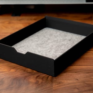 May include: A black rectangular tray with a gray felt liner. The tray is made of a sturdy material and has a modern design.