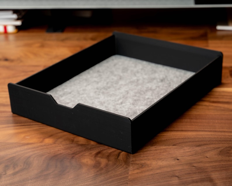 May include: A black rectangular tray with a gray felt liner. The tray is made of a sturdy material and has a modern design.