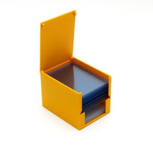 May include: A mustard-yellow storage box with an open lid, containing a stack of clear plastic sleeves. The box is designed to store and protect the contents. The box is made of plastic.